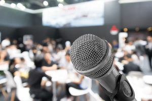 Microphone with blurred photo of conference